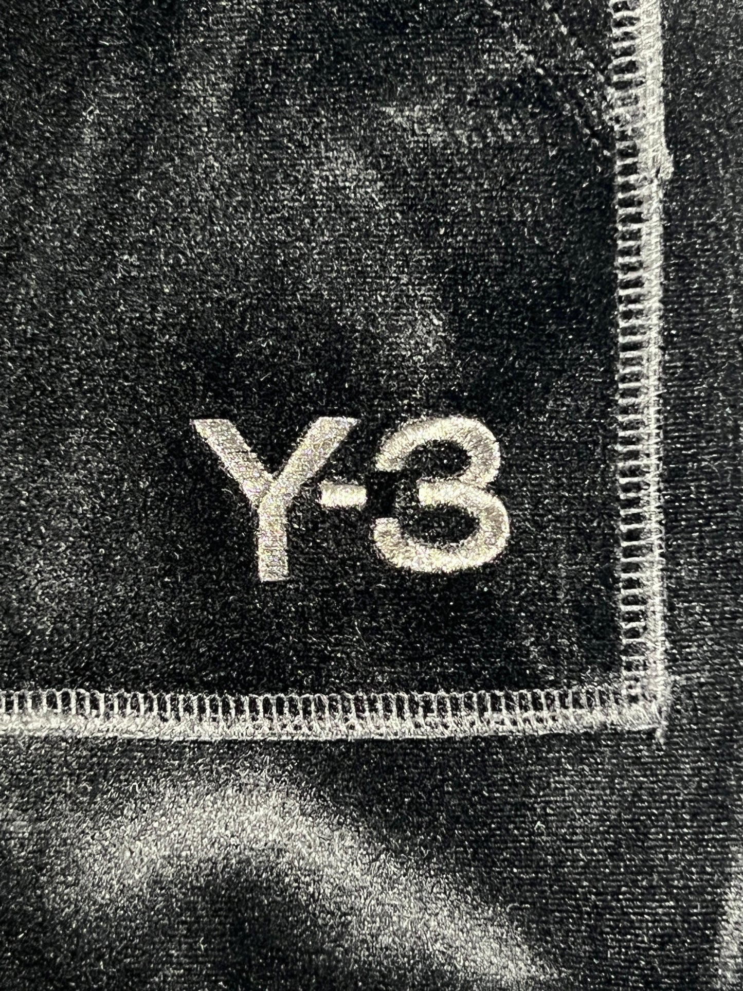 A close up of a Y-3 HOODIE IL2149 VELVET FZ HDY BLACK with the ADIDAS x Y-3 logo on it.