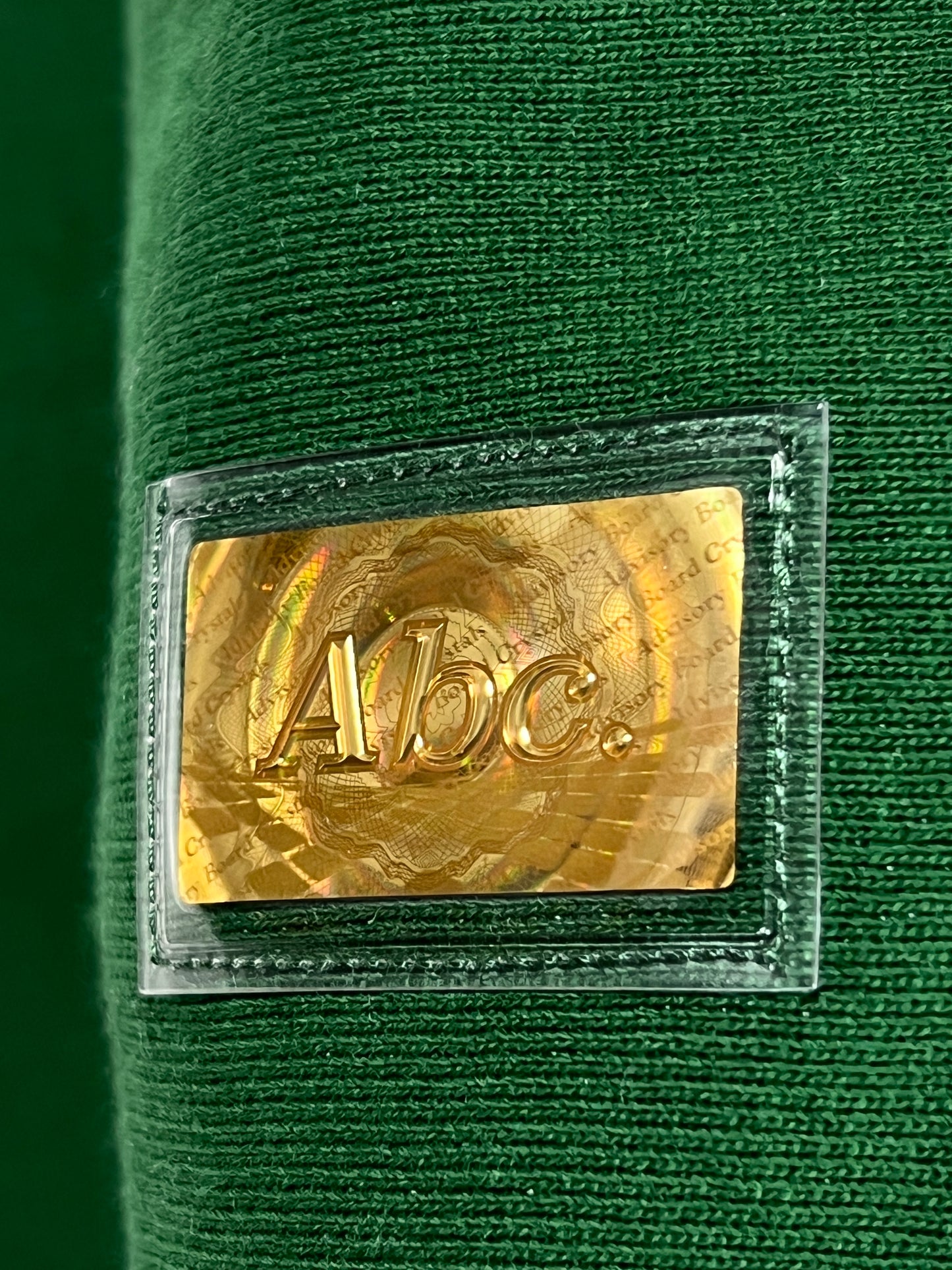 A close up of a green ADVISORY BOARD CRYSTALS pullover hoodie with a gold label on it.