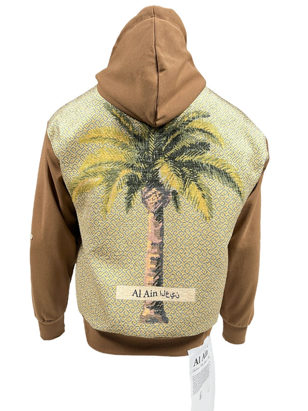 This AL AIN AHOX S102 PALMIER CHAMEAU hoodie features a bold palm tree graphic on a brown hooded sweatshirt, offering a streetwear look with the text "Al Ain" on the back. Made from 100% cotton for ultimate comfort and style.