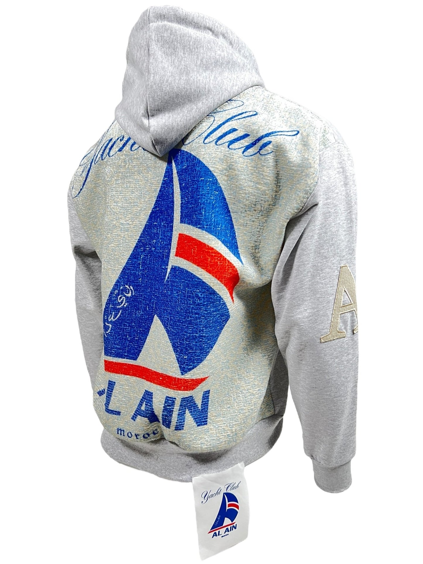 A grey AL AIN AHOX S150 YACHT LIMITED hoodie with a large blue and red sailboat graphic and "Yacht Club Alain" printed on the back. Made from 100% cotton, the front features patches with the letter "A" and a small tag with the same sailboat logo.