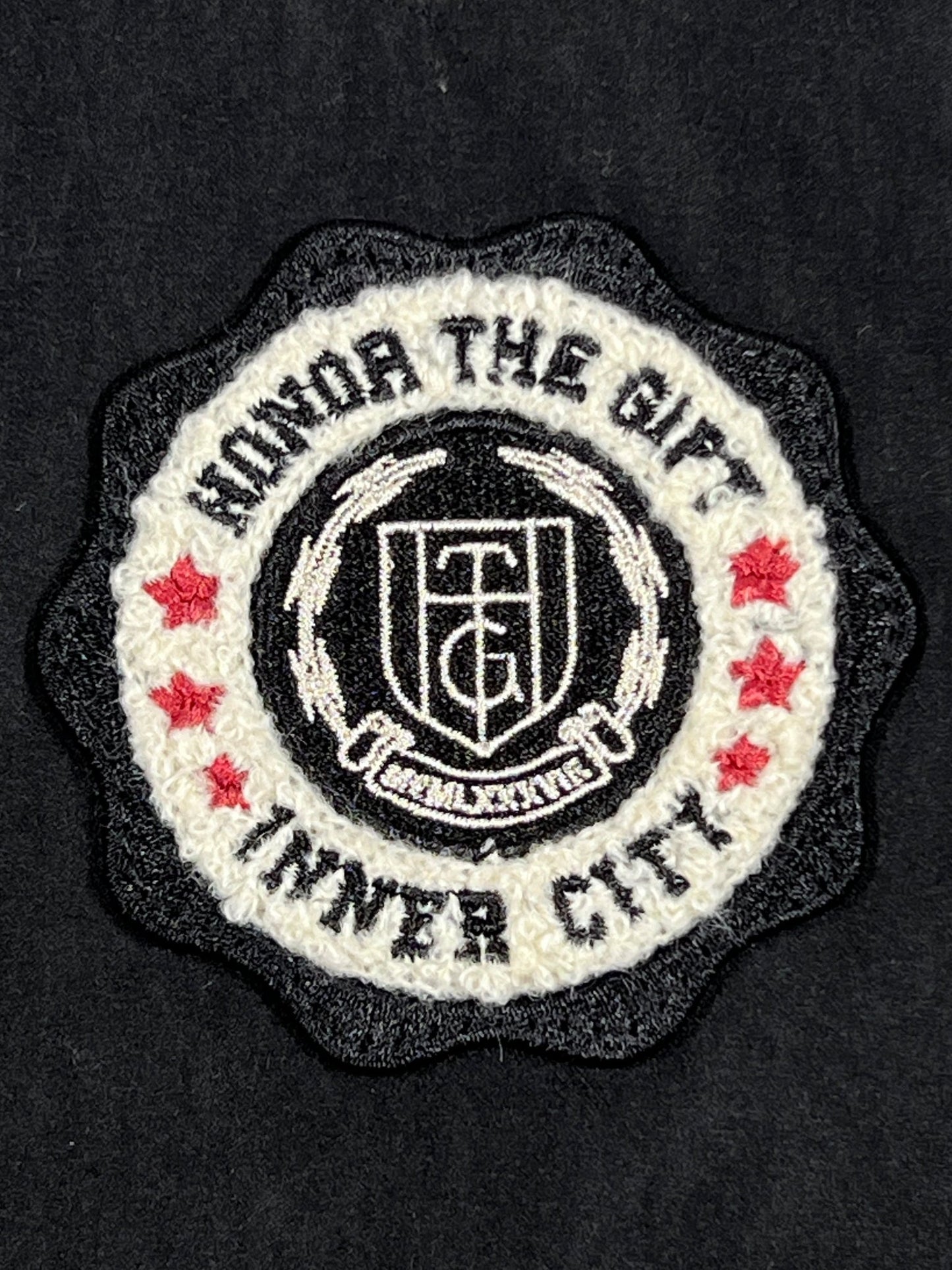 Chenille patch featuring a shield with "HONOR THE GIFT" text, a central monogram, surrounded by "MIND THE GAP" and four red stars on a black background.