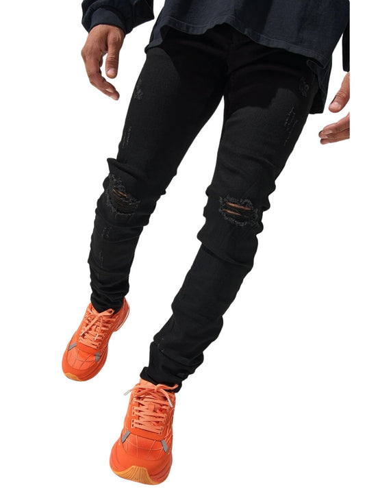 A person wearing SERENEDE midnight black jeans and bright orange sneakers stands with hands partially visible.