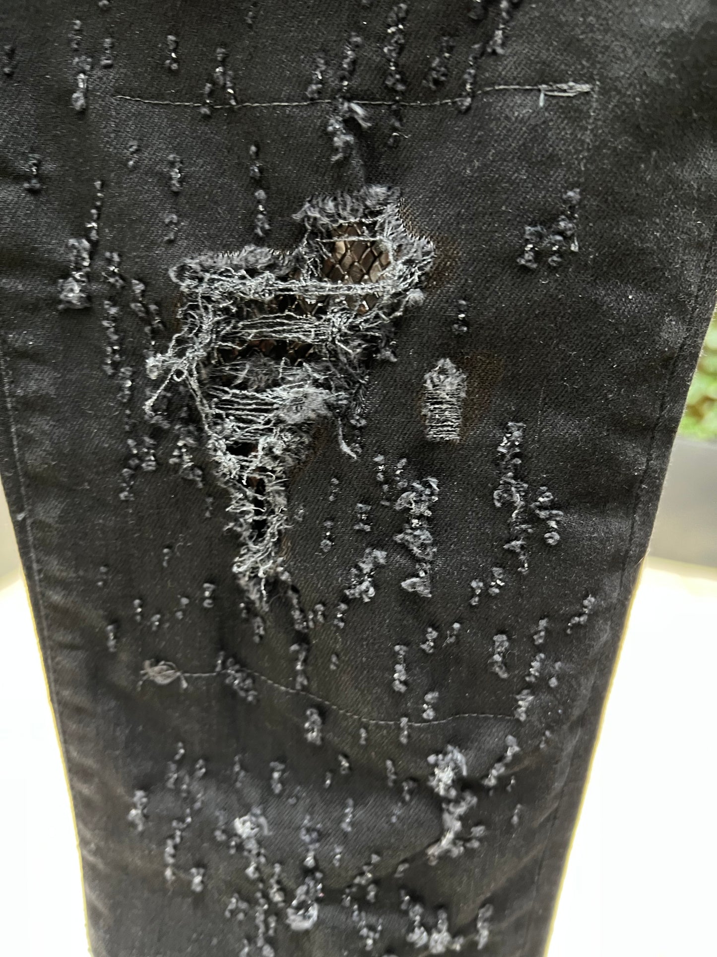 Close-up of RH45 JD18 TORNADO JEANS BLACK distressed premium denim fabric with visible tears and frayed threads.