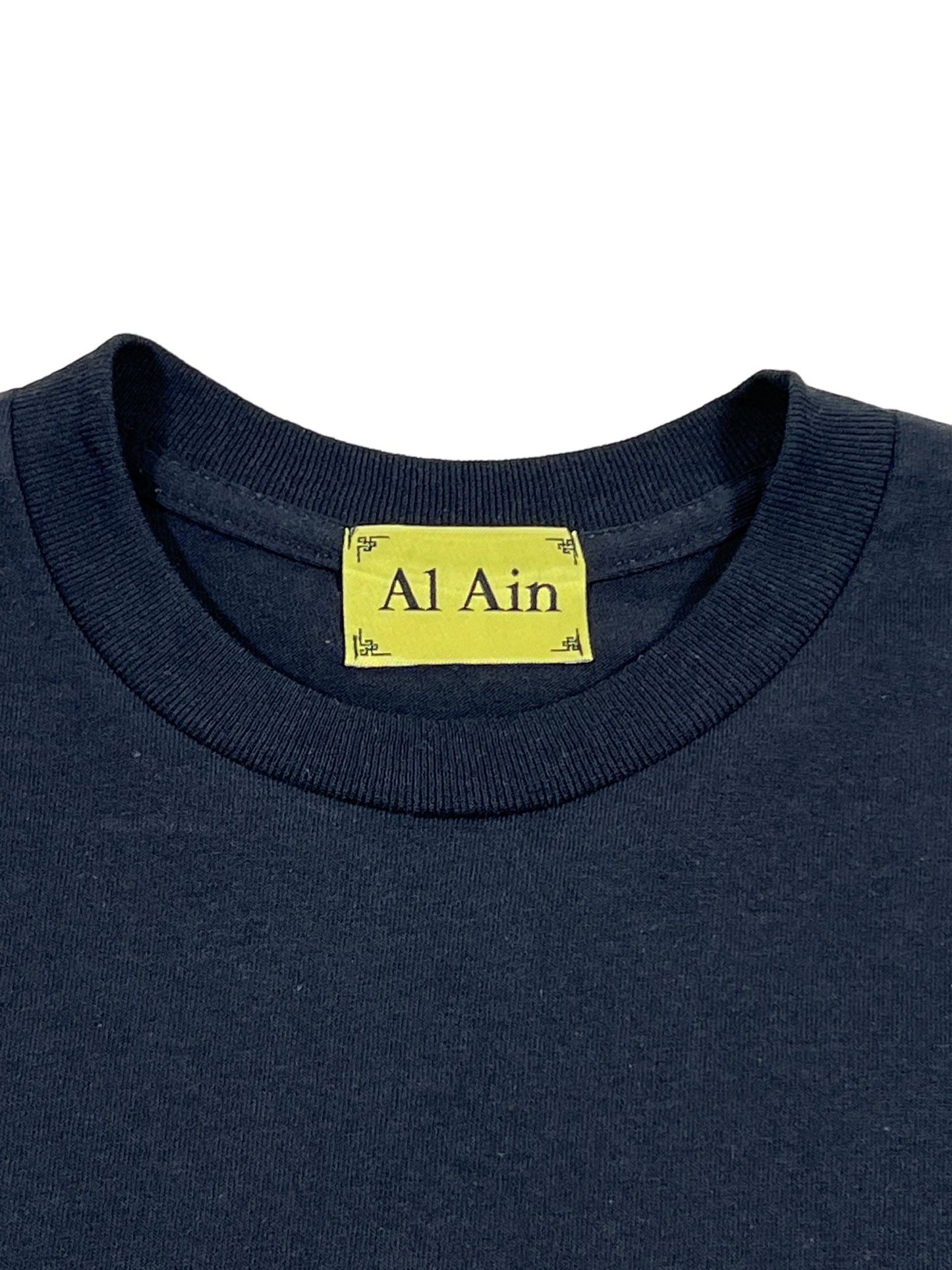 A stylish and eye-catching black T-shirt features a tag emblazoned with the text "AL AIN AMHX S124 CHILL NOIR." This graphic T-shirt effortlessly combines comfort and flair, making it a must-have addition to your wardrobe.