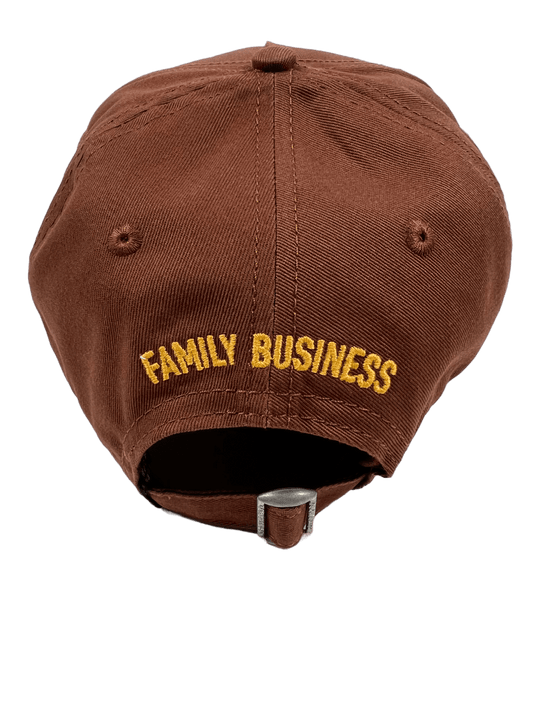 A brown DSQUARED2 BCM0611 BASEBALL CAP GABARDINE-NOCCIOLA with the word "family business" embroidered on it.