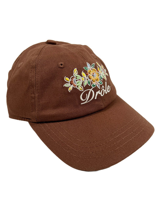 A brown, cotton hat with embroidered flowers on it from DRÔLE DE MONSIEUR DROLE DE MONSIEUR HAT B-CP112 LA CASQUETTE DROLE FLEURIE BROWN.