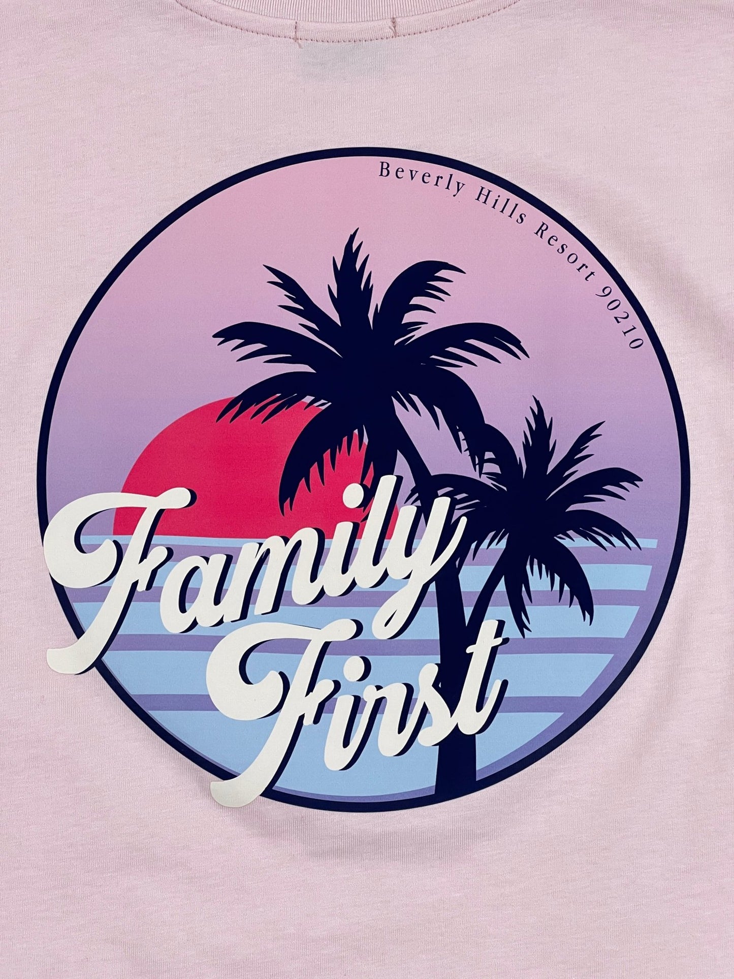 A pink graphic FAMILY FIRST t-shirt with palm trees and the word "family first", made in Italy.