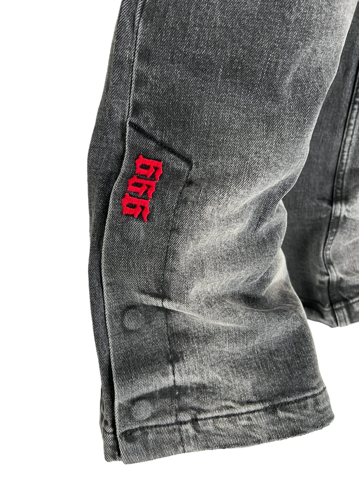 A pair of KSUBI 999 BRONKO CARGO JEANS BLACK with a red embroidery branding on them.