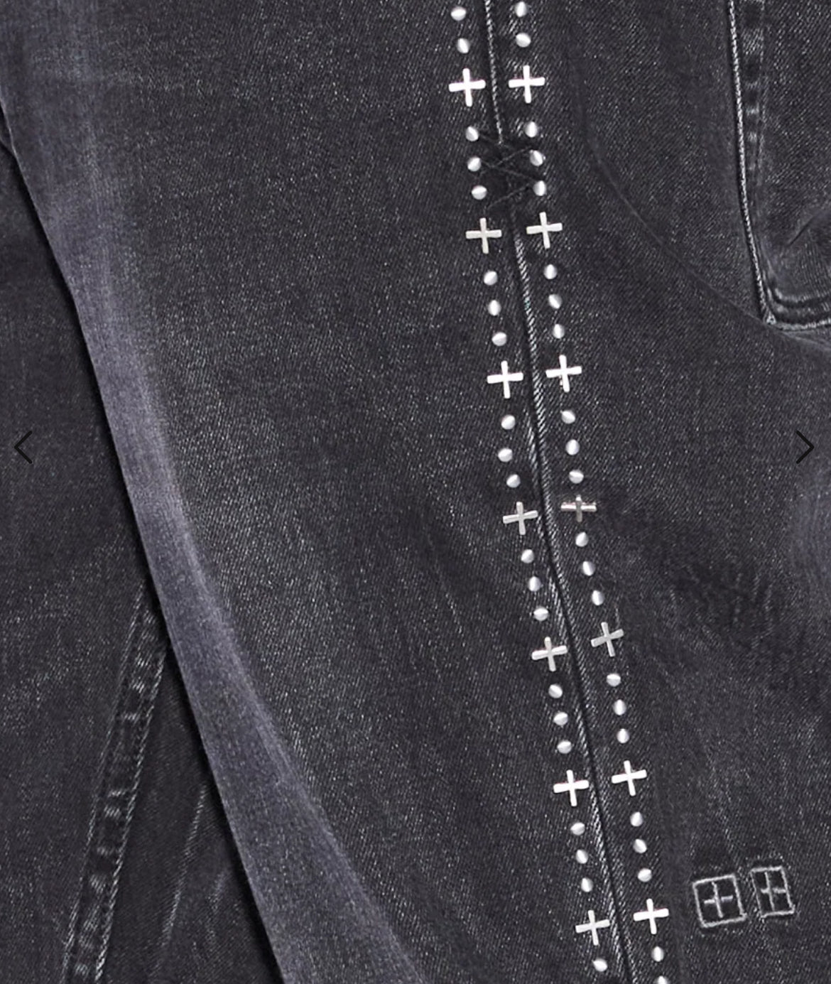 A close up of a pair of KSUBI jeans with cross stitching.