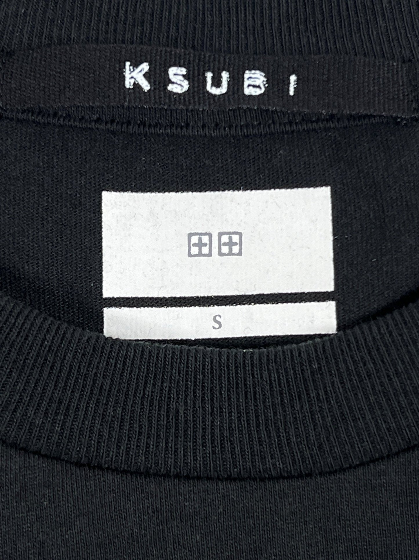 Image of a KSUBI SPACE PALM BIGGIE SS TEE JET BLACK, crafted from 100% cotton, with a visible clothing label displaying the brand name KSUBI and size 'S'.