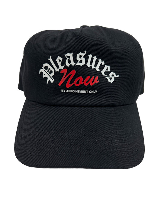 A PLEASURES APPOINTMENT UNCONSTRUCTED SNAPBACK BLK hat, in an edgy style, black with the word "pleasures" now on it.