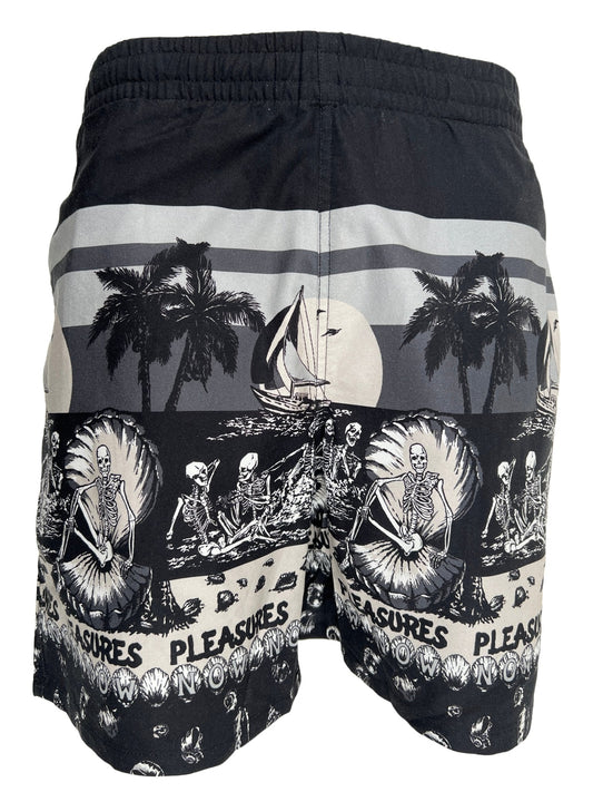 A black PLEASURES BEACH SHORT BLACK with palm trees and skeletons on it.