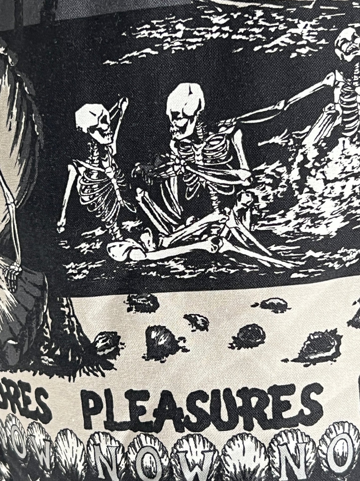 A black and white poster with skeletons wearing PLEASURES BEACH SHORT BLACK on it.