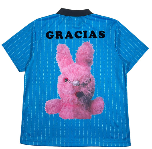 A PLEASURES blue shirt made of technical micromesh fabric with a pink bunny on it that says gracias.