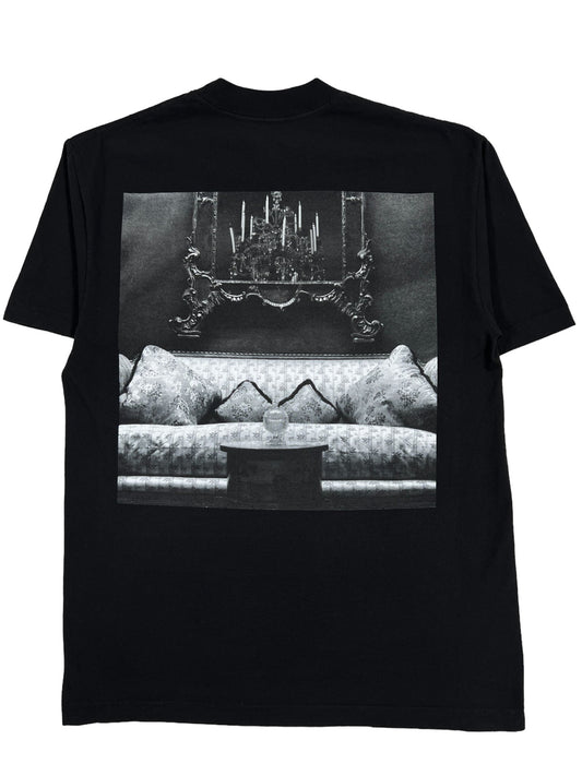 A 100% cotton PLEASURES COUCH T-SHIRT BLACK featuring an image of a couch from PLEASURES.