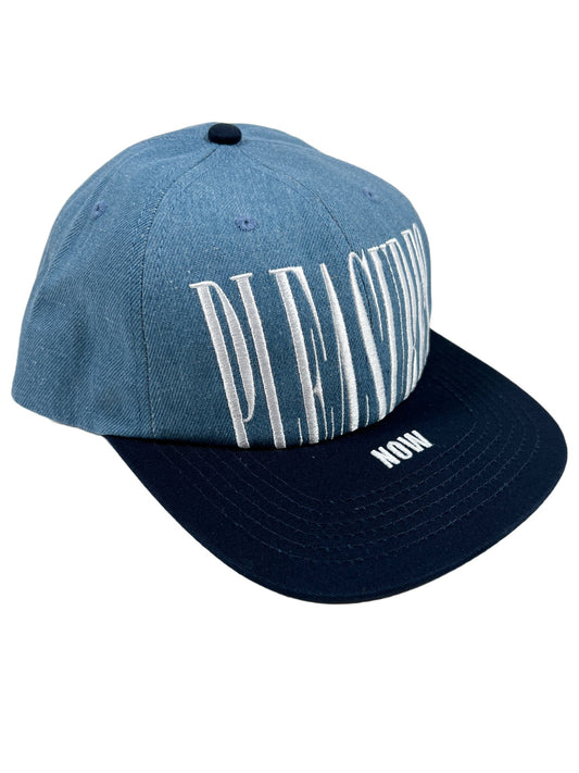 A blue PLEASURES STRETCH SNAPBACK DENIM ball cap with the word 'Pleasure' embroidered on it.