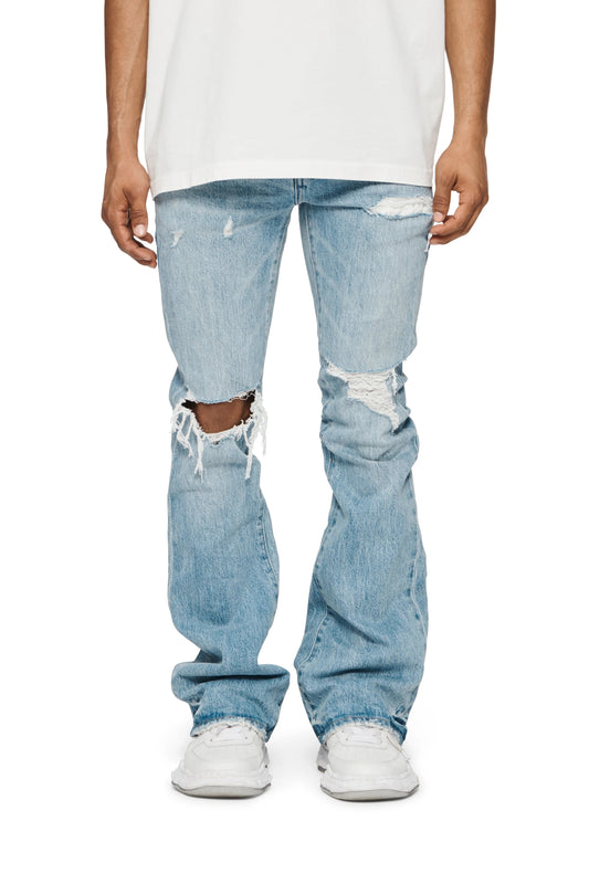 A man wearing PURPLE BRAND P004-RPFL RIPPED FLARE LT INDIGO jeans and a white t-shirt.