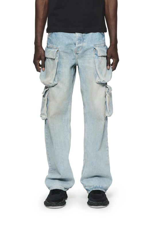 A man wearing Purple Brand P018-BGLI relaxed double cargo LT indigo pants with cargo pockets and a black t-shirt.