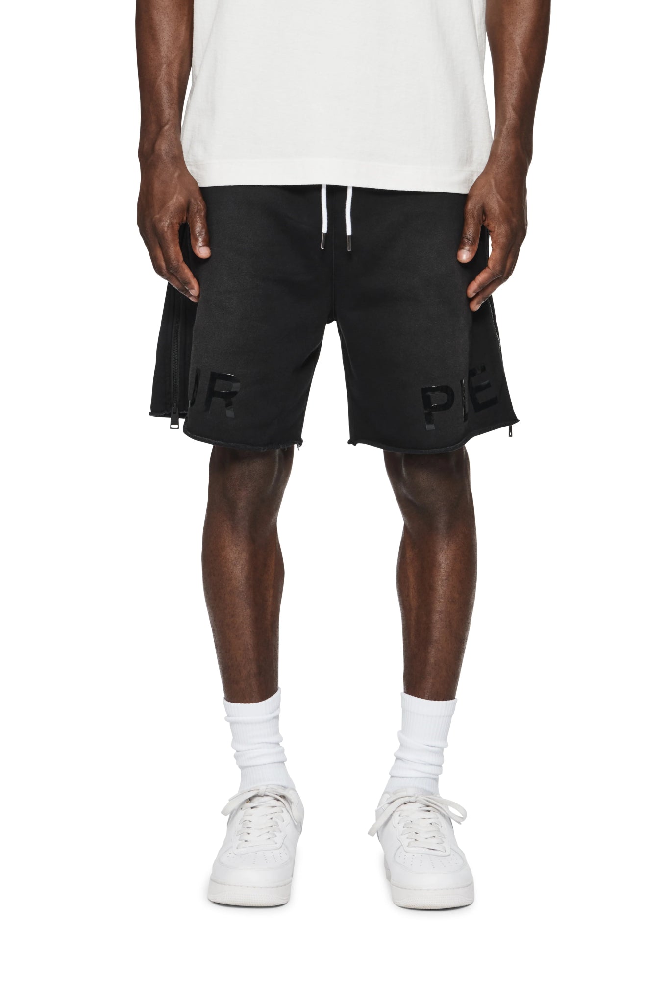 A person wearing a white T-shirt, PURPLE BRAND P479-MFBW MWT FLEECE SWEATSHORT BLACK with the letters "RP" partly visible on the front, white socks, and white sneakers.