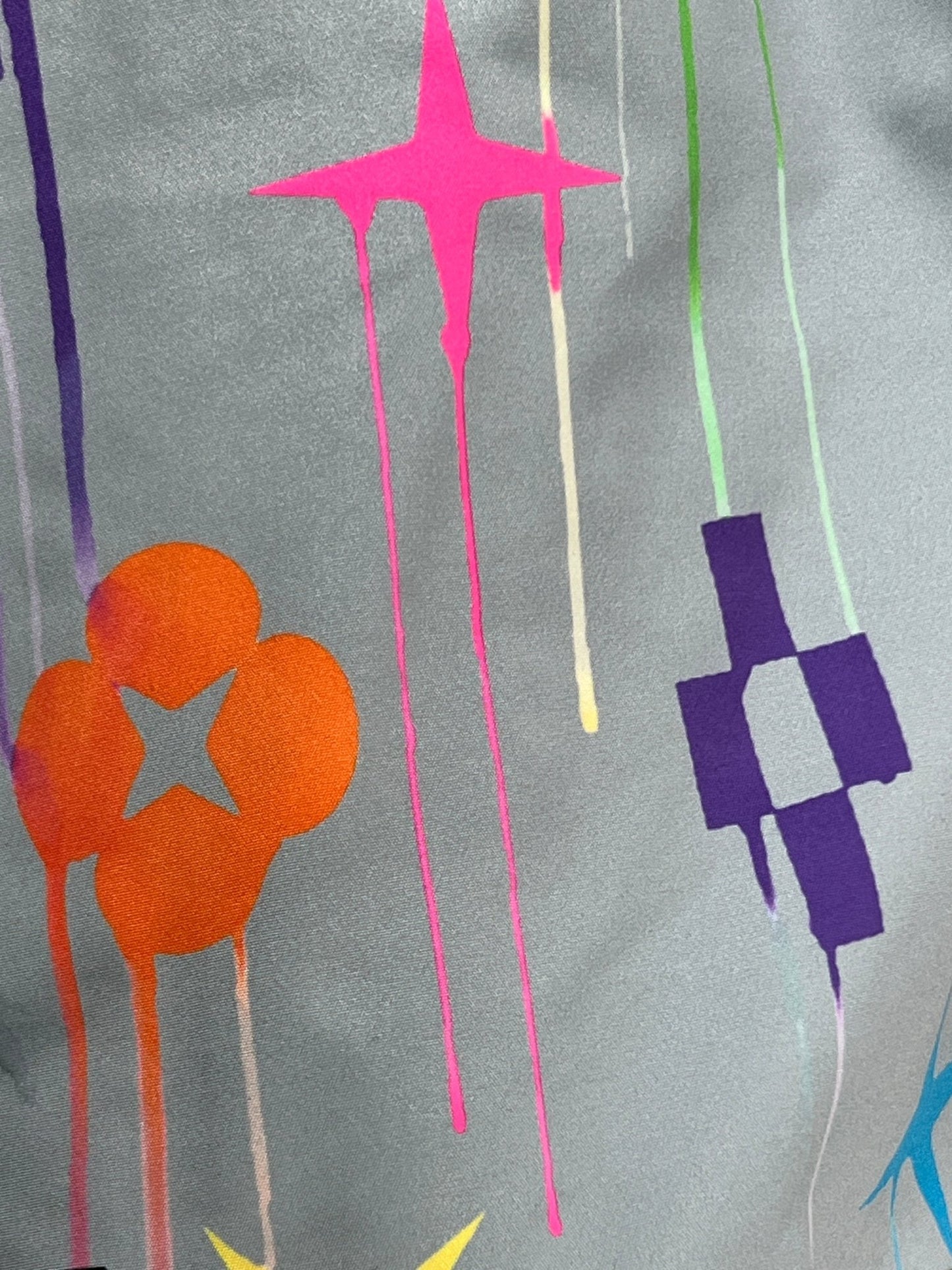 Colorful star, flower, and geometric shapes are spray-painted on a gray surface. Some paint drips down the surface, creating a vibrant print that's both playful and unique. This is exemplified in the PURPLE BRAND P504-PGPM ALL ROUND SHORT AOP by PURPLE BRAND.
