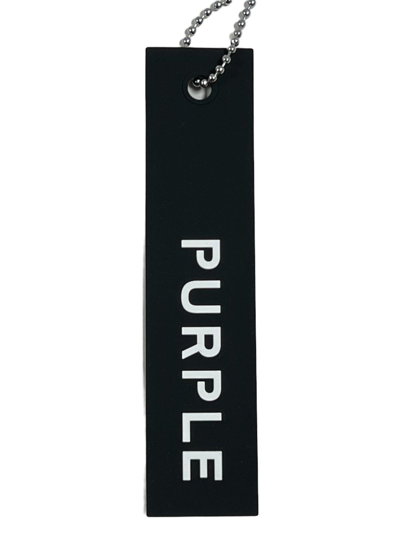A black keychain tag with the text "PURPLE" in white, attached to a silver ball chain, reflecting the vibrant print and unique design of PURPLE BRAND P504-PGPM ALL ROUND SHORT AOP swim trunks by PURPLE BRAND.