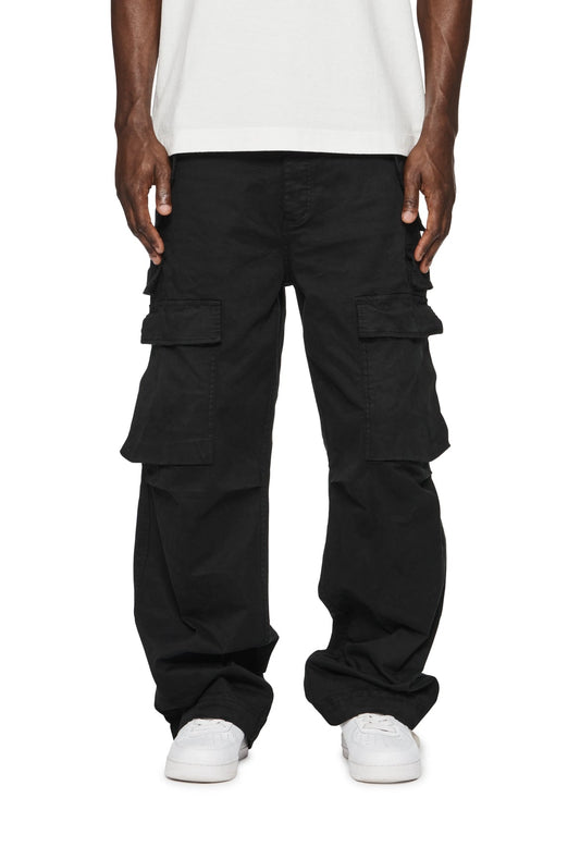 A man wearing a Purple Brand cargo pant P527-DCWB double pocket cargo BLK with multiple pockets and a white t-shirt.
