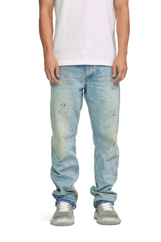 A man wearing a white t-shirt and PURPLE BRAND JEANS P011-VDPI VINTAGE DARTY PAINTED LT INDIGO.