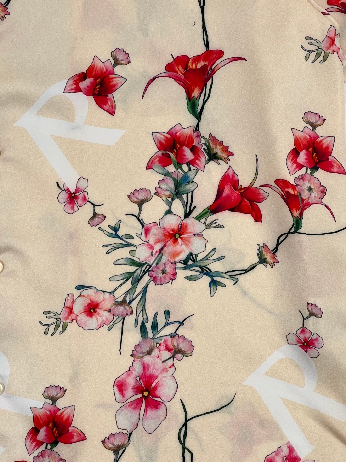 A close up of a REPRESENT M06108 FLORAL SHIRT CREAM with red flowers on it, featuring a Cuban collar.