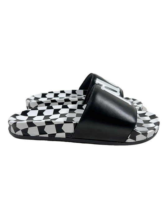 A pair of RHUDE black and white checkered leather slides with a rubber sole.
