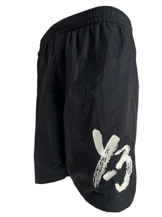 A black ADIDAS x Y-3 swim shorts with a white logo on it.