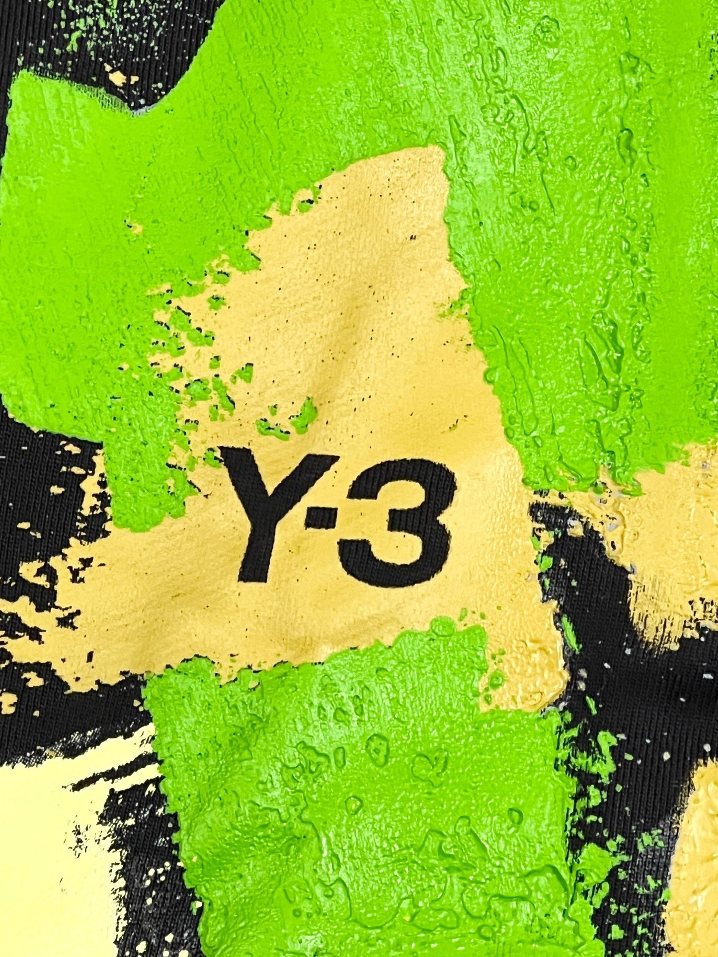 A green and yellow painting with the Y-3 HOODIE IP5580 GFX FT FZ HOOD BLACK on it, symbolizing an organic cotton logo hoodie from ADIDAS x Y-3.