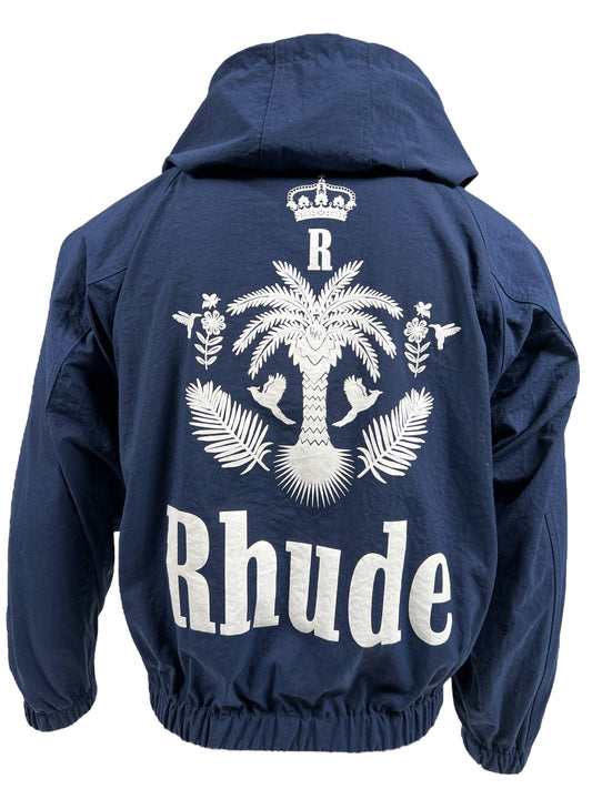 A RHUDE PALM TRACK JACKET NAVY by RHUDE, in navy blue nylon with a large white graphic on the back featuring a palm tree, birds, leaves, a crown, and the text "Rhude".