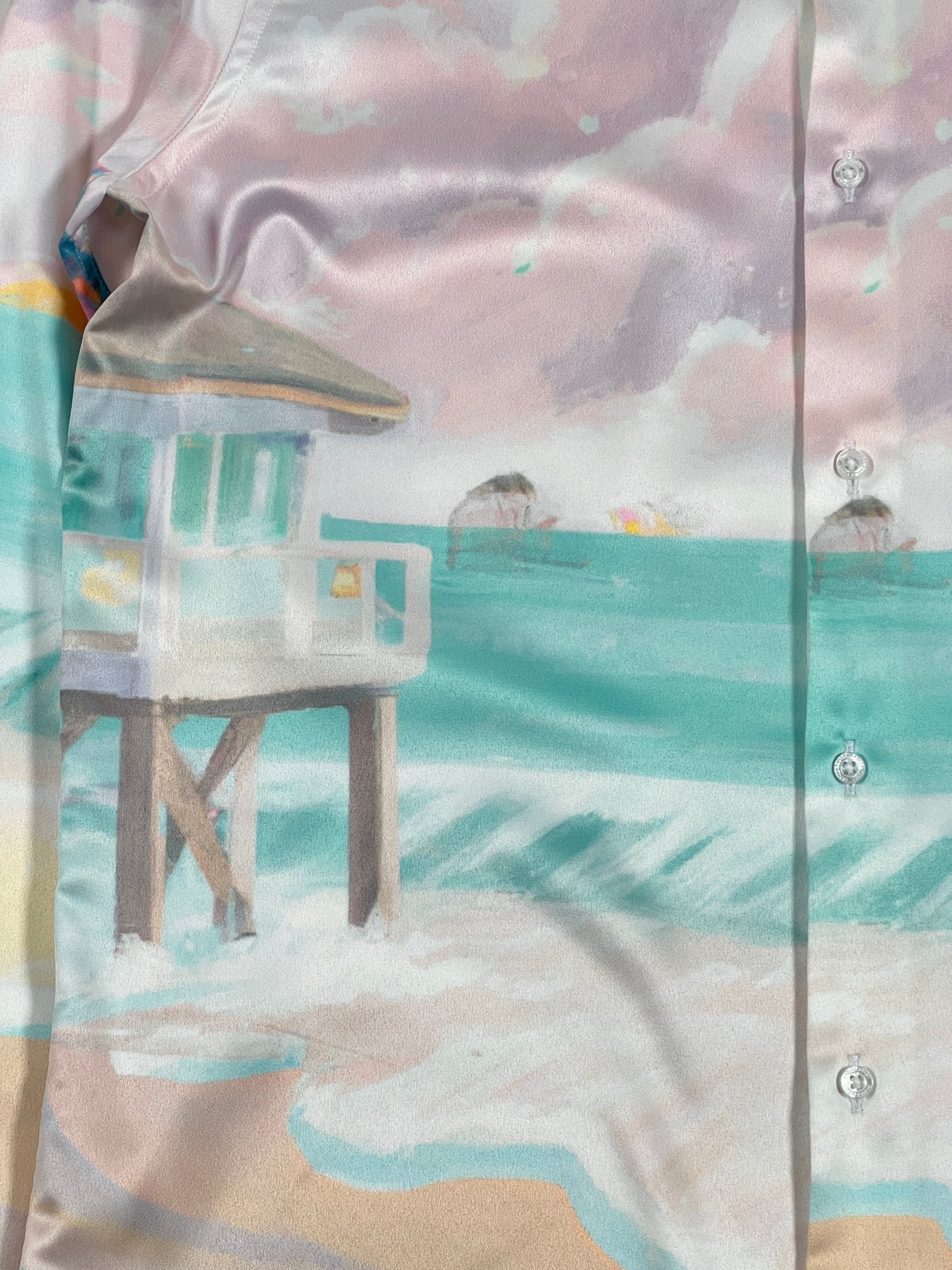 A long sleeve FAMILY FIRST Hawaiian shirt made in Italy with a painting of a beach and a lifeguard tower.