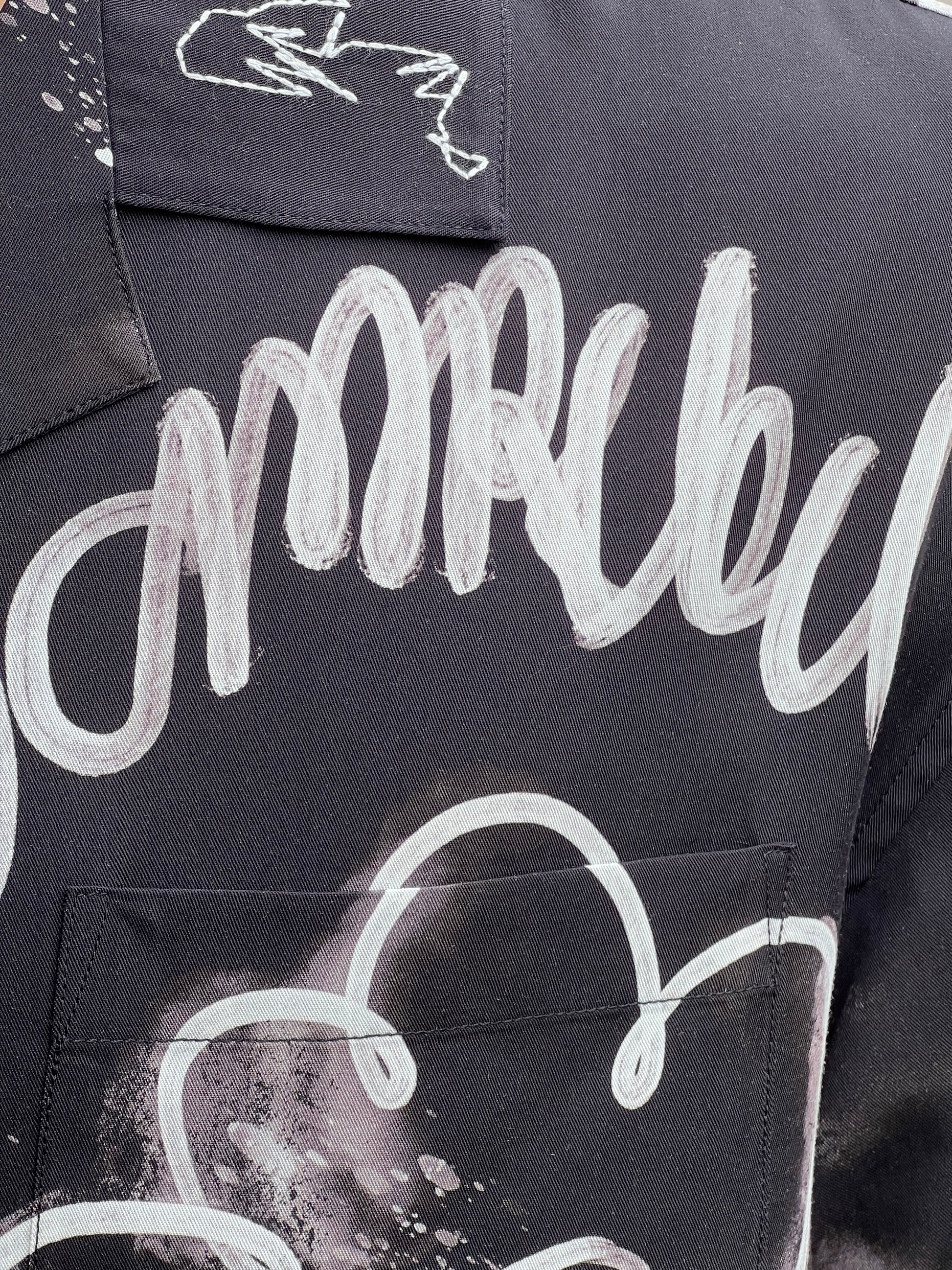 Close-up of a DOM REBEL DOMREBEL CHAINED SHIRT BLACK featuring an all-over print with dark fabric and abstract white graffiti-style patterns and lettering. The fabric is a smooth rayon Tencel blend.