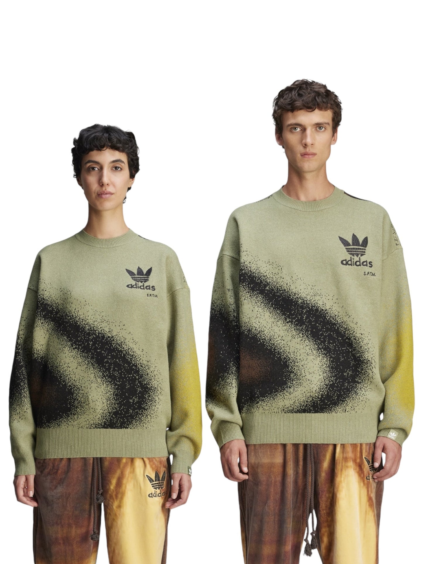 Two models don matching collaboration sweaters from the ADIDAS x SONG FOR THE MUTE collection, specifically the Adidas X Song For The Mute Ji9643 Adi004 Knitswea Tengr. These feature black and yellow gradient patterns on a green base. They complement these with brown pants, all set against a crisp white background.