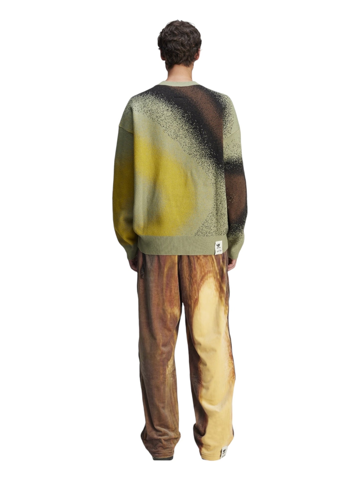 A person wearing the Adidas X Song For The Mute Ji9643 Adi004 Knitswea Tengr, featuring abstract patterns, paired with wide-legged pants from the Song for the Mute collection, as seen from behind.