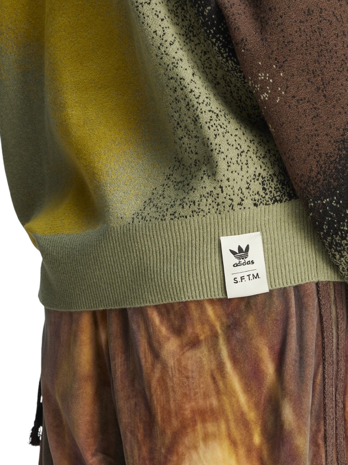 A close-up of a striking ensemble featuring an Adidas X Song For The Mute Ji9643 Adi004 Knitswea Tengr piece. This textured shirt with "S.F.T.M." text pairs brilliantly with colorful pants, exemplifying bold style and innovative design from the collaboration between ADIDAS x SONG FOR THE MUTE.