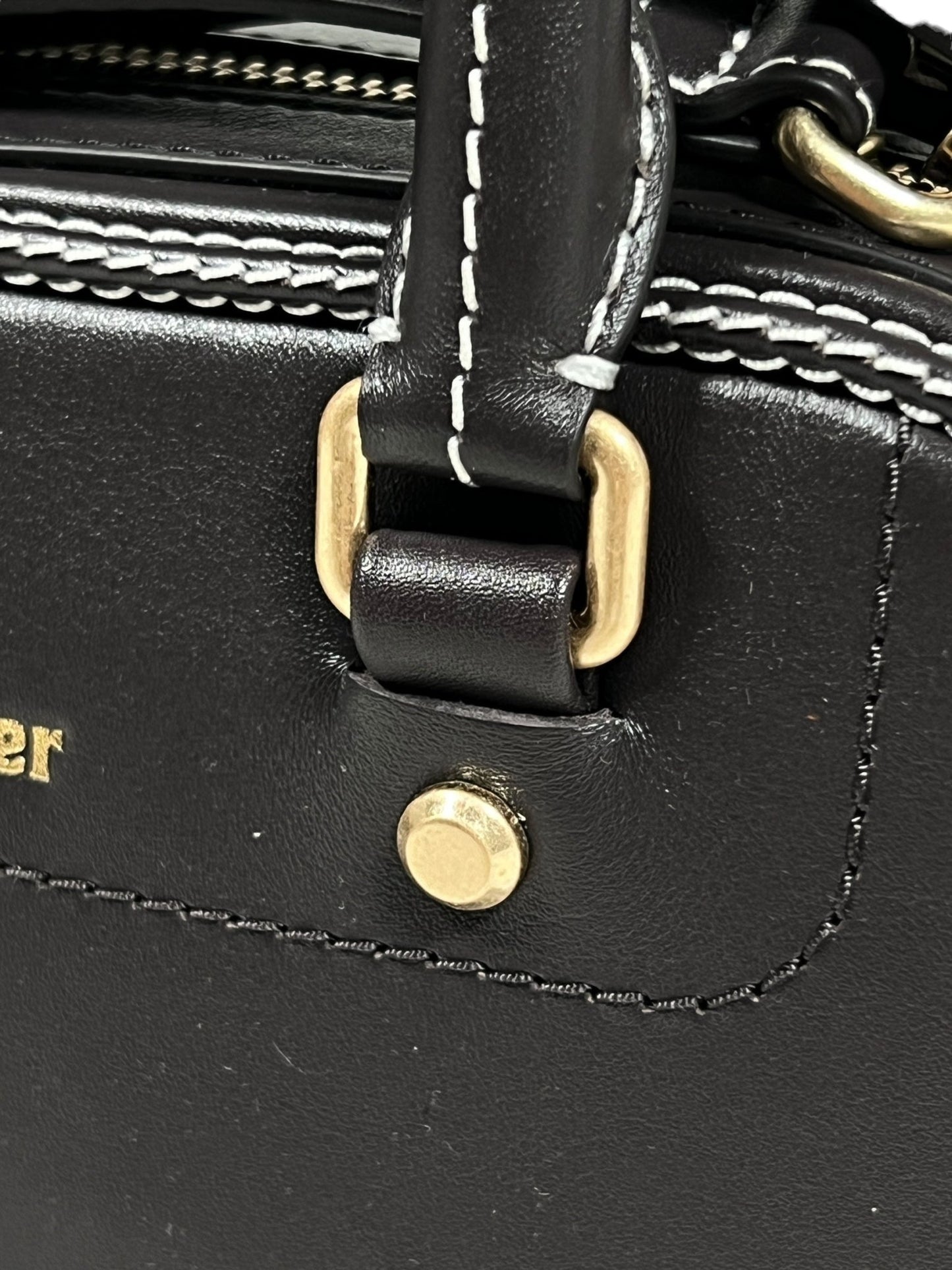 Close-up of an Adidas x Wales Bonner black leather bag featuring white stitching, a brass buckle, and a round brass stud, reminiscent of the exquisite craftsmanship seen in their collaboration.