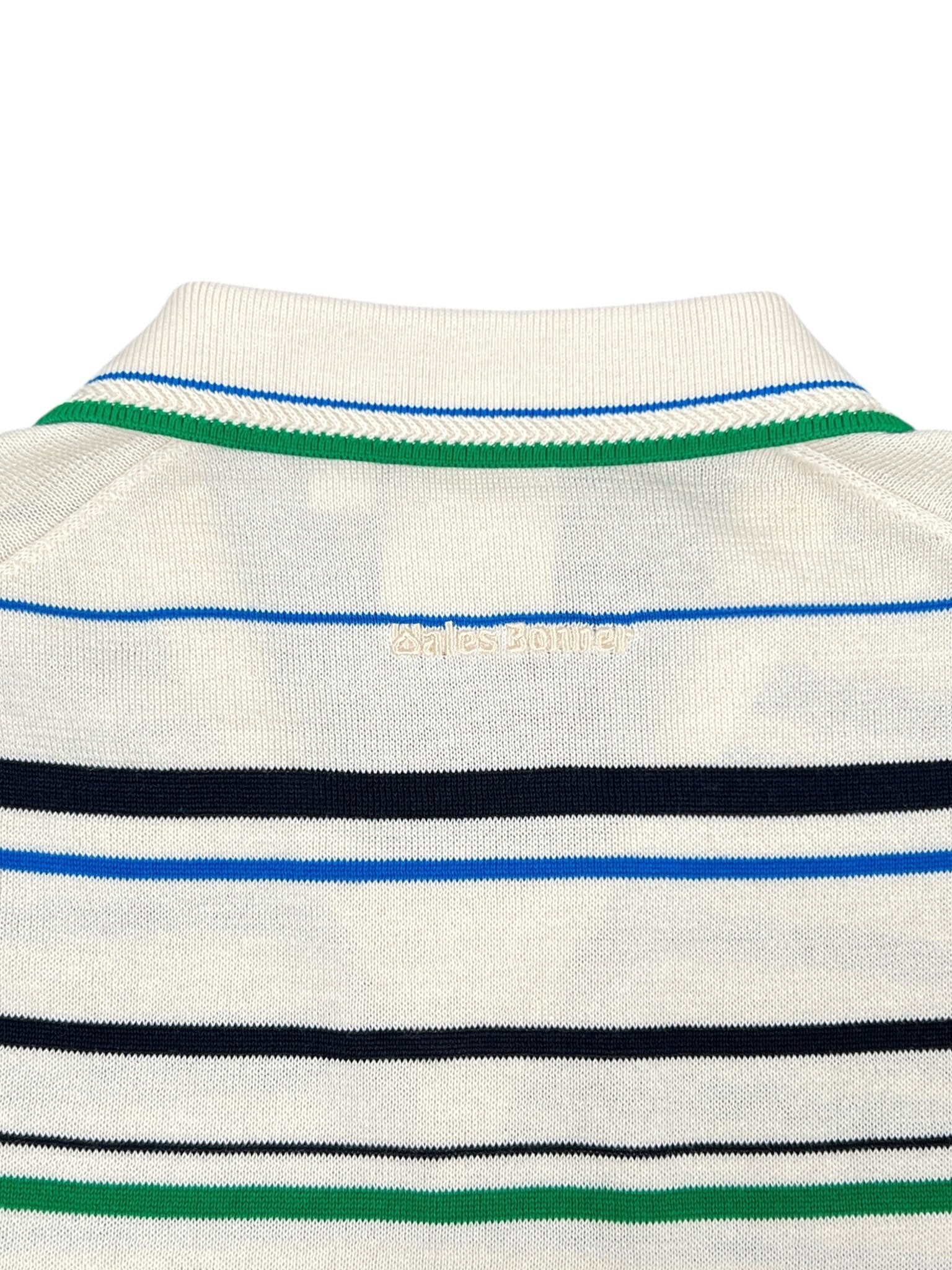 Close-up of the back neckline of the ADIDAS x WALES BONNER JM8203 WB Knit Polo WonWh, a cream sweater with blue, green, and black stripes, featuring "wales bonner" embroidered in yellow, nodding to a classic striped polo style.