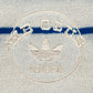 Close-up of the Adidas x Wales Bonner JM8203 WB Knit Polo WonWh, showcasing green and blue horizontal stripes and a beige embroidered circular logo—a vintage-inspired piece from ADIDAS x WALES BONNER.