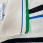 Close-up of the Adidas x Wales Bonner JM8203 WB Knit Polo WonWh, a cream-colored polo with blue and black stripes, green and blue-edged collar, vintage-inspired design, and visible tag.