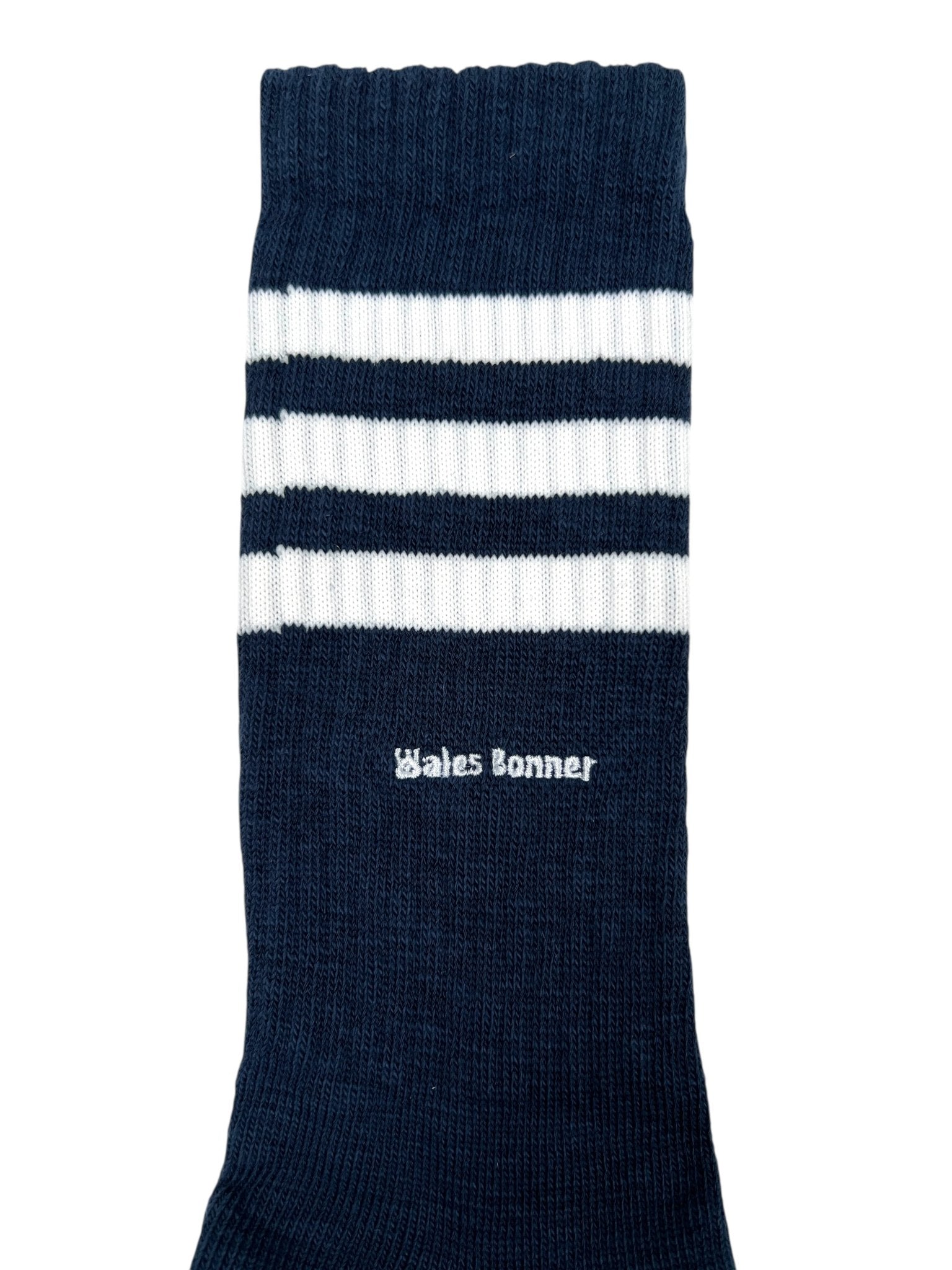 The Adidas x Wales Bonner JV8684 WB 3S Sock in navy features two white horizontal stripes near the top and “Wales Bonner” embroidered below the stripes.