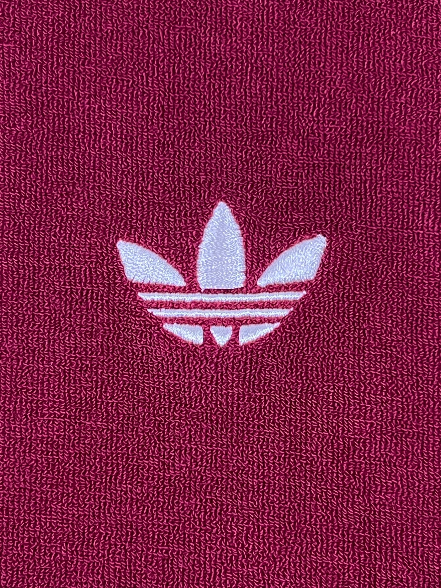 The Adidas x Wales Bonner JW1122 WB Terry Polo Cburg features a white Adidas Trefoil logo embroidered on textured maroon fabric, adding retro flair and sporty elegance to your style.