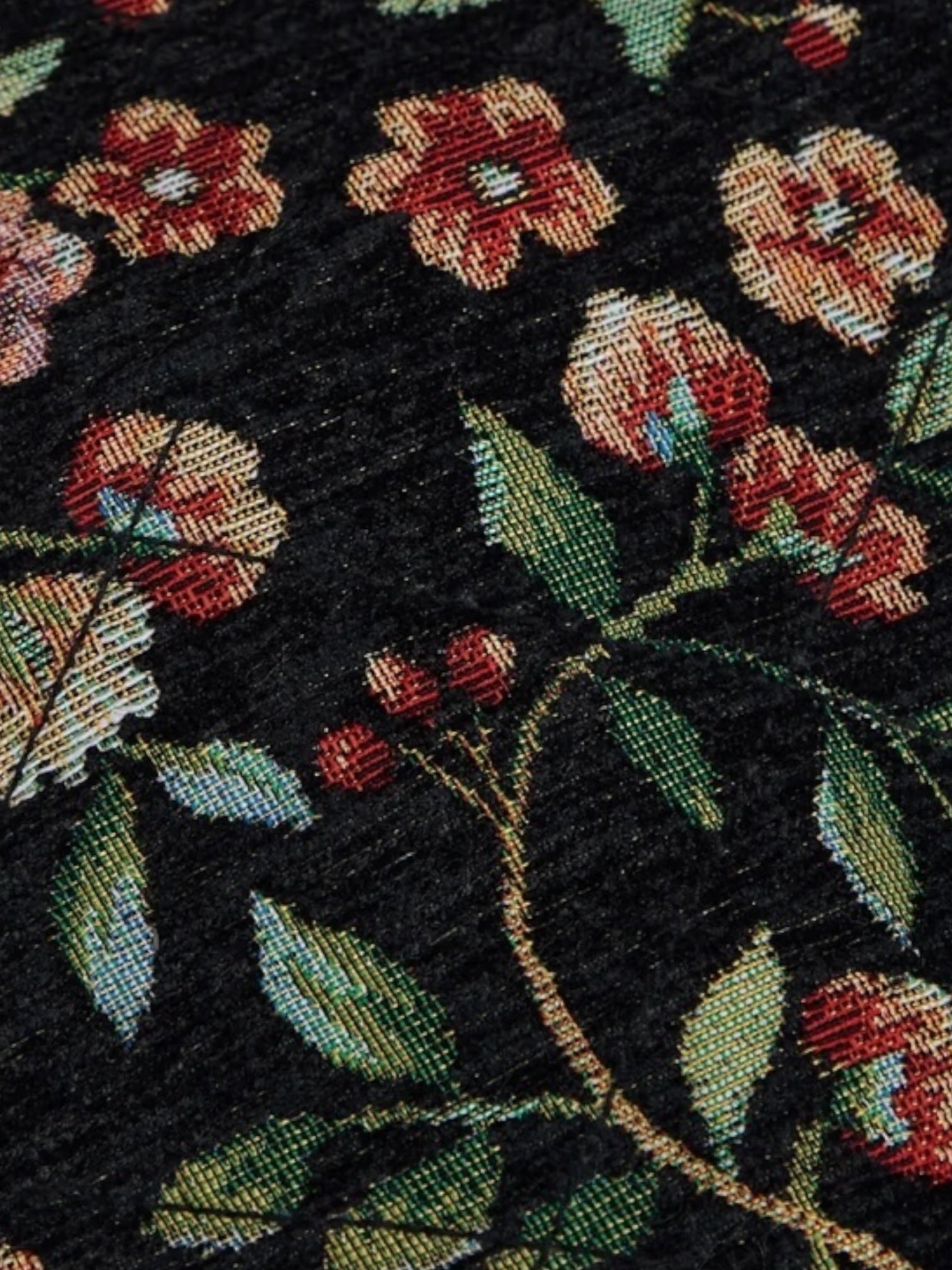 Close-up of the Advisory Board Crystals Abc. Floral Jacquard & Canvas Jacket in black by ADVISORY BOARD CRYSTALS, featuring a detailed Japanese paisley floral pattern with red and pink flowers and green leaves woven into the dark fabric.