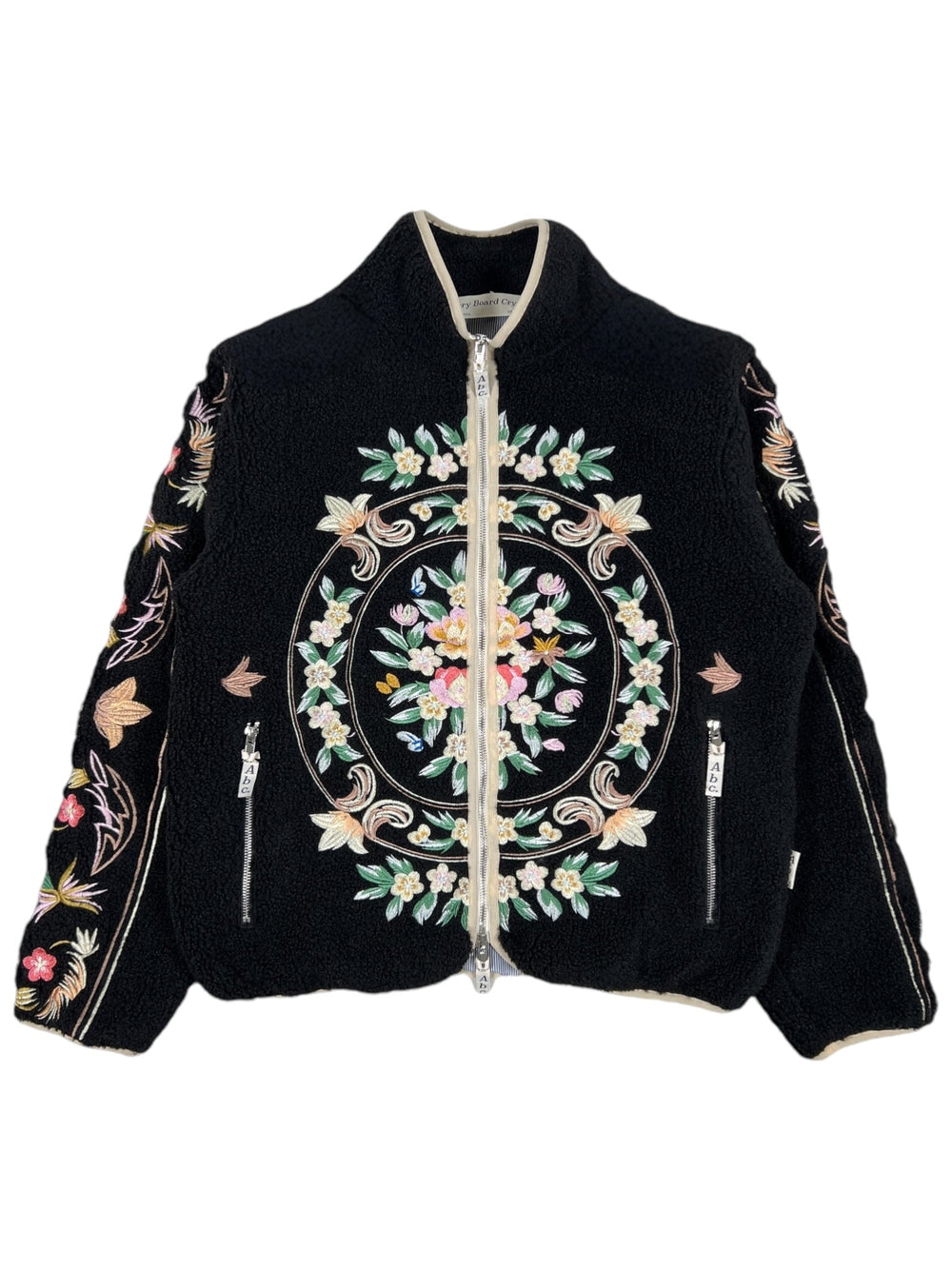 Introducing the Advisory Board Crystals Floral Fleece Zip-Up Black by ADVISORY BOARD CRYSTALS. This polyester jacket is embellished with detailed floral embroidery on the front and sleeves, showcasing a central circular floral motif and a practical zippered front, echoing the distinctive style of Advisory Board Crystals' designs.