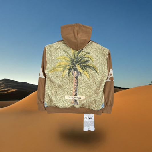 A thick rope texture lace jacket with a palm tree design and the text "AL AIN AHOX S102 PALMIER CHAMEAU" displayed on a stand in a desert setting.