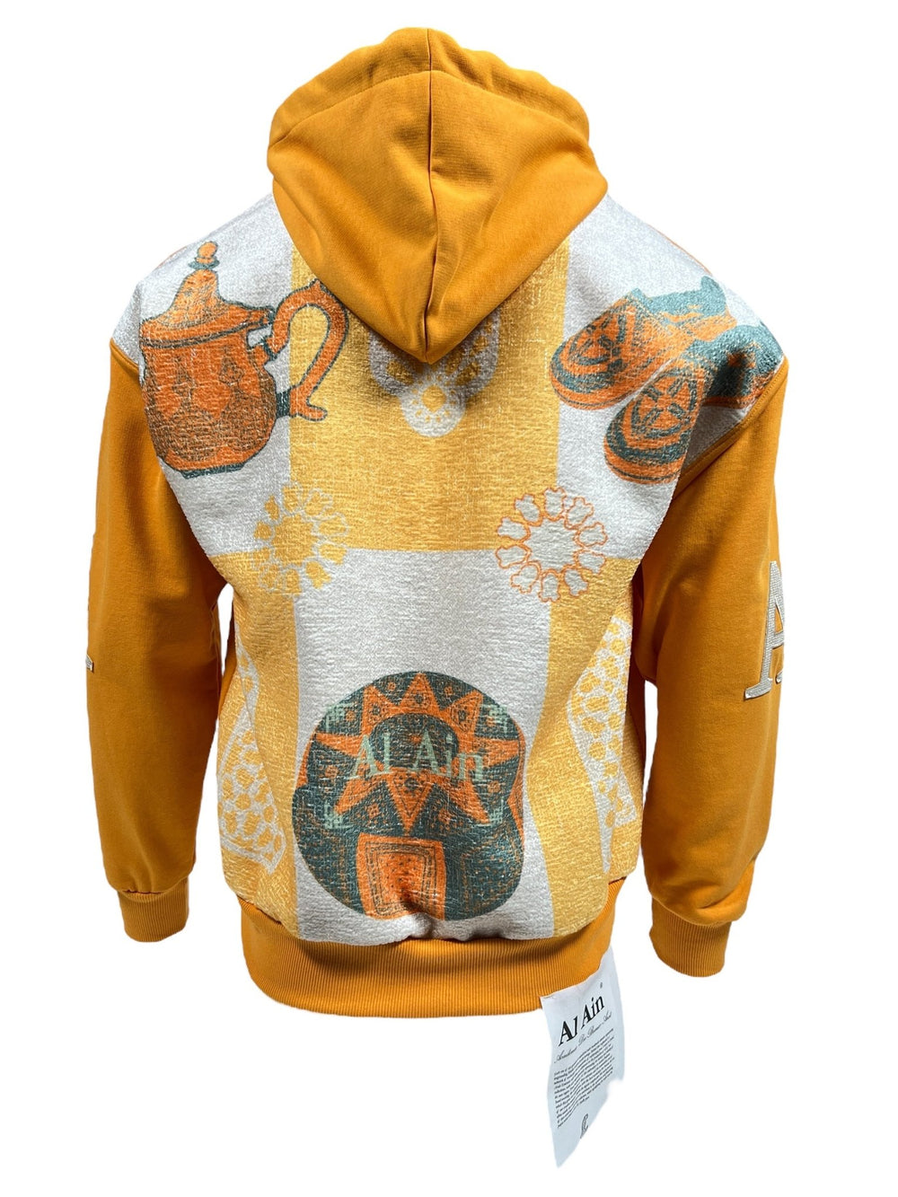 Introducing the Al Ain AHOX S108 Pouvoir Ocre by AL AIN: a stunning ocre yellow hoodie made entirely from 100% cotton. This piece features intricate teapot, shoe, and geometric designs on the back, perfect for adding a unique flair to your streetwear collection.