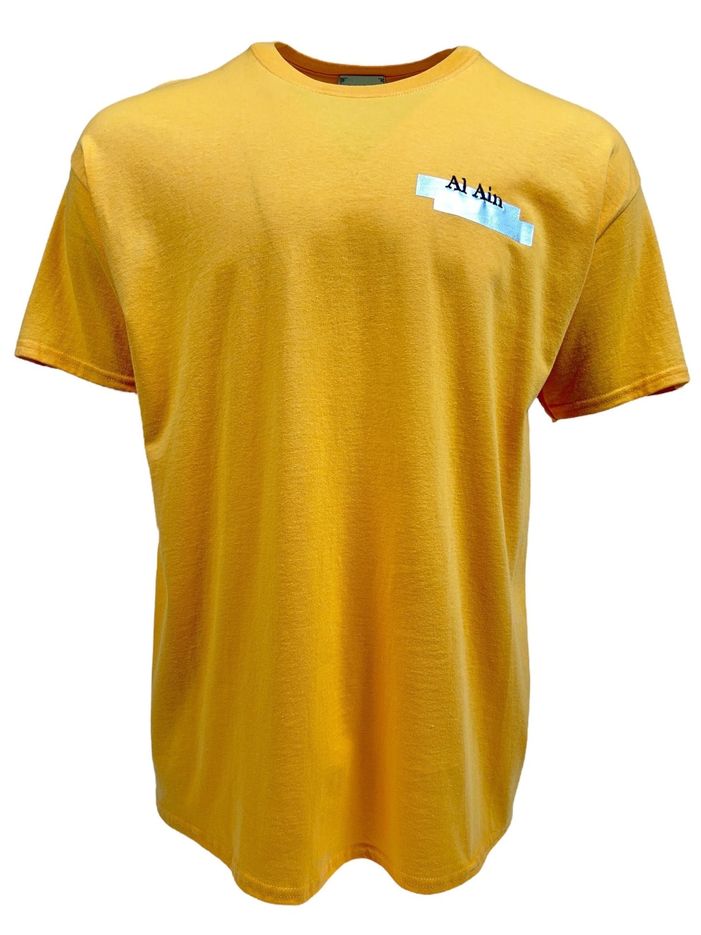 The Al Ain AMHX S120 Jabalia Ocre is a yellow graphic t-shirt made from 100% cotton, featuring a small embroidered label on the upper left chest with the text "Al Ain.