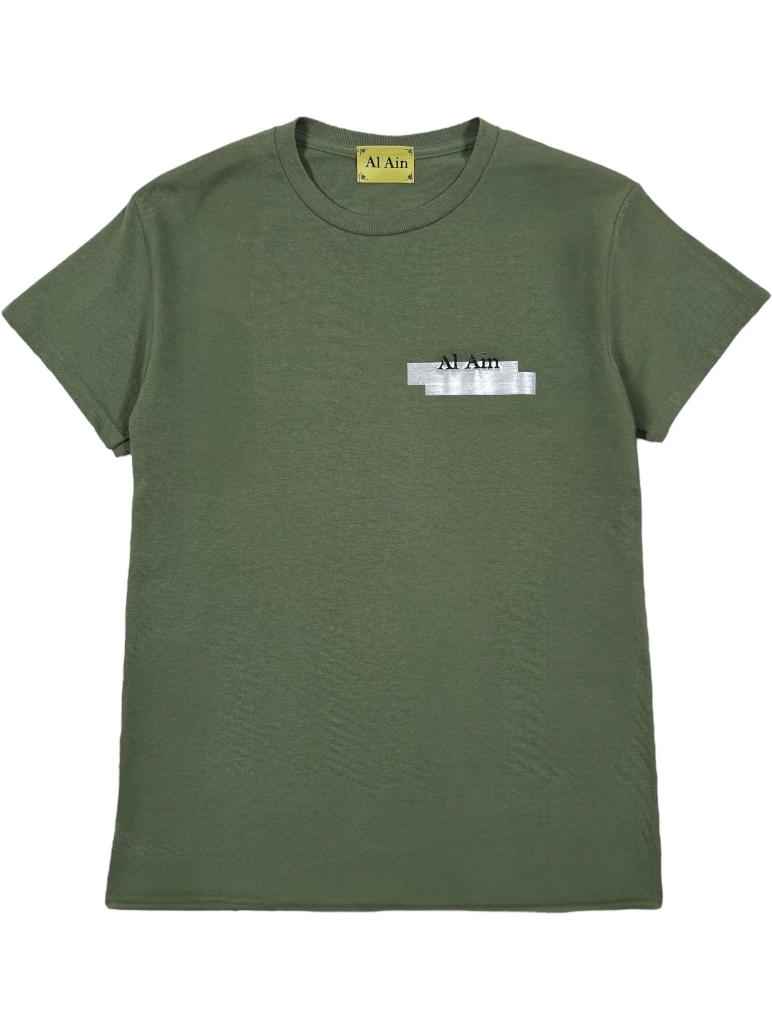 The Al Ain AMHX S121 Peacock Militaire by AL AIN is an olive green short-sleeve graphic t-shirt with a yellow "Al Ain" neck label and an embroidered "AL AIN" logo on the left chest, partially covered by a gray strip.