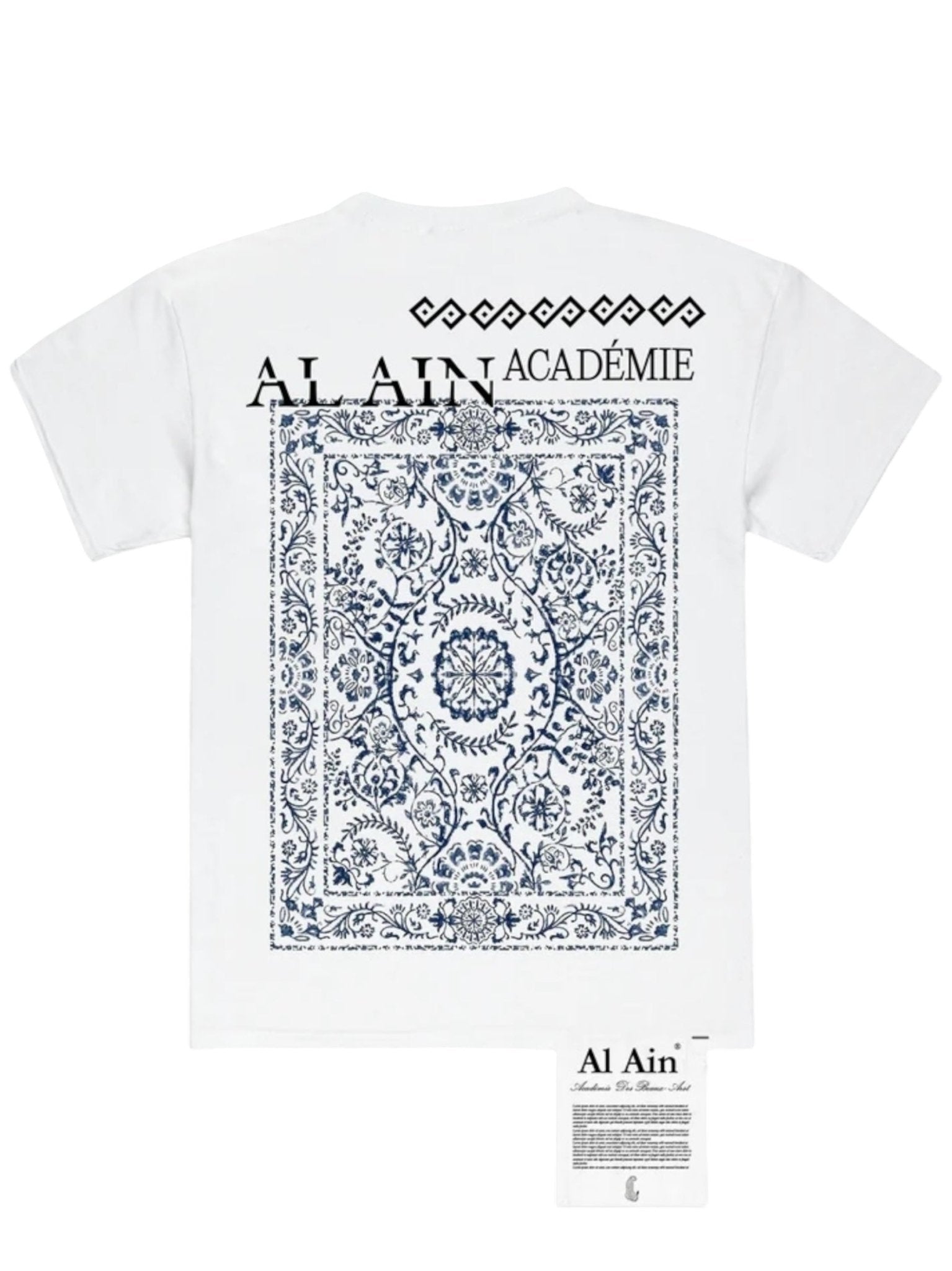 The AL AIN Al Ain AMHX-S817 Sekaya T-shirt White is made in Italy from 100% cotton, featuring a blue ornate floral and geometric design with "AL AIN ACADÉMIE" above it and a small printed tag at the bottom.